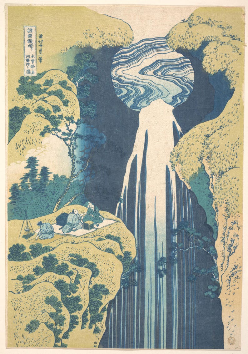 May include: A Japanese woodblock print featuring a tall, stylized waterfall cascading between beige cliffs with dark blue foliage. Three figures sit on a mat on a cliffside ledge, with a small tripod stove nearby. Japanese text appears in the upper left.