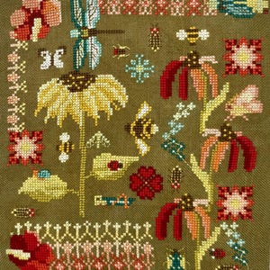 May include: A cross-stitch embroidery on olive green fabric featuring a variety of insects including a blue dragonfly, bees, and beetles, interspersed with yellow and red flowers, geometric floral patterns, and decorative border elements.