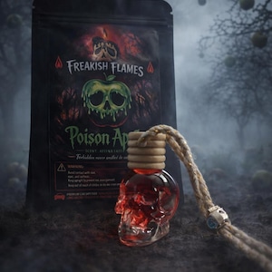 May include: A skull-shaped glass car air freshener filled with red liquid, featuring a wooden cap and a hanging rope. Behind it stands a black pouch labeled Freakish Flames Poison Apple, displaying a graphic of a skull-shaped green apple.