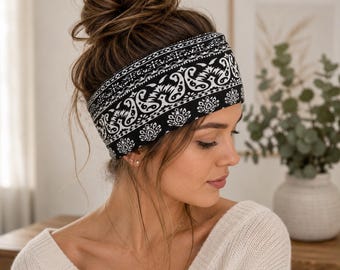 Peut inclure: Un large bandeau en tissu arborant un motif cachemire noir et blanc. L'accessoire présente un design complexe et répétitif avec des motifs floraux et en forme de goutte sur toute la surface, offrant un contraste marqué sur le front.