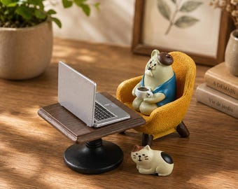 Peut inclure: Une figurine miniature représentant un ours portant un béret et une chemise bleue, assis dans un fauteuil jaune tout en tenant une tasse à café blanche. Un ordinateur portable argenté est posé sur une petite table brune, avec un chat miniature.