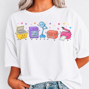 Puede incluir: Una camiseta blanca con un estampado gráfico colorido de cinco herramientas de manualidades antropomórficas con caras sonrientes, que incluyen un limpiador ultrasónico amarillo, un horno morado, una lámpara de lupa azul, una nevera naranja y una plastificadora rosa.