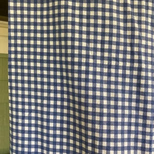 May include: Close-up of a blue and white checkered fabric. The pattern is a classic gingham design, with small, evenly spaced squares. The fabric appears to be cotton or a similar material, with a slightly textured surface. The color scheme is a deep blue and white.