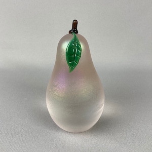 May include: A pear-shaped glass figurine with an iridescent finish and a green glass leaf on top.