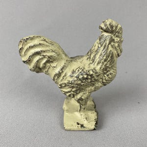 May include: A white ceramic mug with a black handle and the text "But First, Coffee" in a bold, black font. The mug is set against a blurred background, suggesting a cozy setting.