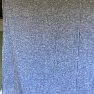 May include: A large, blue and white textured fabric hanging from a clothesline. The fabric has a gradient effect, transitioning from a darker blue at the top to a lighter blue at the bottom. The fabric is made of a soft material.
