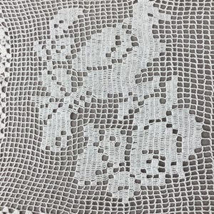 May include: A white, handmade crochet doily with a floral design in the center. The doily features a delicate, openwork pattern and a scalloped edge. The intricate details and texture of the crochet work are clearly visible.
