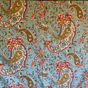 May include: A blue fabric with a paisley pattern in shades of brown, pink, and white. The fabric is covered in small floral designs.