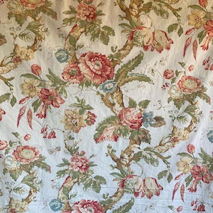 May include: Cream-colored fabric with a repeating floral pattern. The design features large, red and pink peonies, smaller yellow and pink flowers, and blue accents. Brown branches and green leaves complete the botanical theme.
