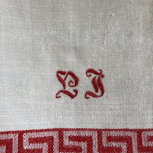 May include: White linen kitchen towel with red embroidered initials "DJ" and a red Greek key border.