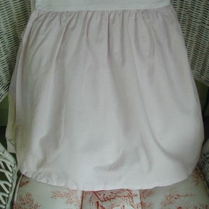 May include: A white wicker chair with a pink ruffled skirt draped over it.