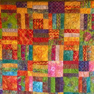 May include: A colorful patchwork quilt with a variety of vibrant fabrics in shades of yellow, orange, red, green, blue, and purple. The quilt features a geometric design with rectangular and square blocks, creating a visually appealing textile.