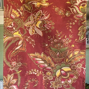 May include: Red fabric with a floral pattern in shades of brown, green, and yellow. The fabric features a paisley design with intricate details.
