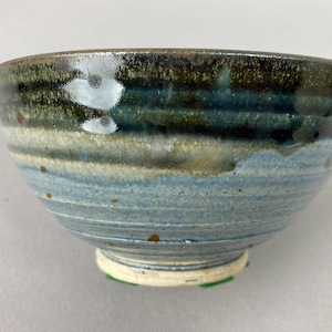 May include: A blue and brown ceramic bowl with a white glaze. The bowl has a wide rim and a rounded bottom. The bowl is handmade and has a unique, rustic look.