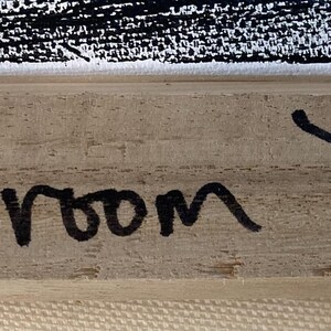 May include: Close-up of a section of a painting with the words "Ballroom Dance" written in black marker on a light-colored wooden frame. The top of the painting has black and white brushstrokes.
