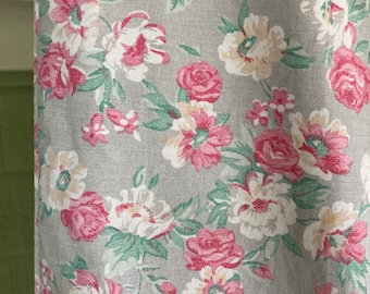 May include: A gray fabric with a floral pattern featuring pink and white flowers. The fabric has a textured surface.