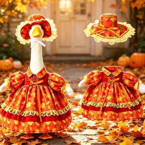 May include: A plush goose wearing a dress and bonnet with an autumn leaf pattern, featuring orange and red colors, lace trim, and a white ribbon tie. A matching dress and bonnet set are displayed separately next to the goose.