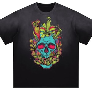 May include: A black short-sleeved t-shirt featuring a vibrant graphic print of a bright blue human skull. The skull is surrounded by various green and yellow carnivorous plants, including pitcher plants and a Venus flytrap, with pink accents.