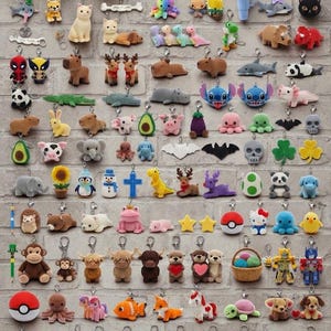 Pode incluir: Uma coleção de vários pequenos porta-chaves de peluche e plástico com animais, criaturas míticas, alimentos, crânios e personagens da cultura pop, dispostos num padrão de grelha contra um fundo de tijolo cinzento claro.