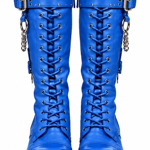 May include: A pair of bright blue knee-high boots featuring a lace-up front with silver-toned eyelets, a thick lug sole, and a top strap with a silver buckle. Each boot includes a decorative silver chain attached to a metal ring on the side.