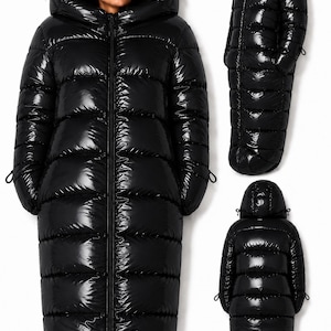 Peut inclure: Un long manteau doudoune noir, brillant et matelassé, doté d'une fermeture éclair frontale intégrale et d'une grande capuche intégrée. Le manteau présente des compartiments horizontaux sur le corps et les manches, avec des cordons.