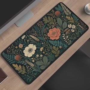 May include: A rectangular desk mat featuring a dark background with a dense botanical pattern of flowers and foliage in shades of coral, cream, sage green, and mustard yellow. The design includes various blossoms, ferns, and leafy stems.