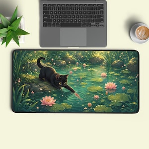 May include: A rectangular desk mat featuring a digital illustration of a black cat reaching out to touch a small fish in a pond filled with pink lotus flowers, green lily pads, and rocks, set against a backdrop of lush green aquatic plants.
