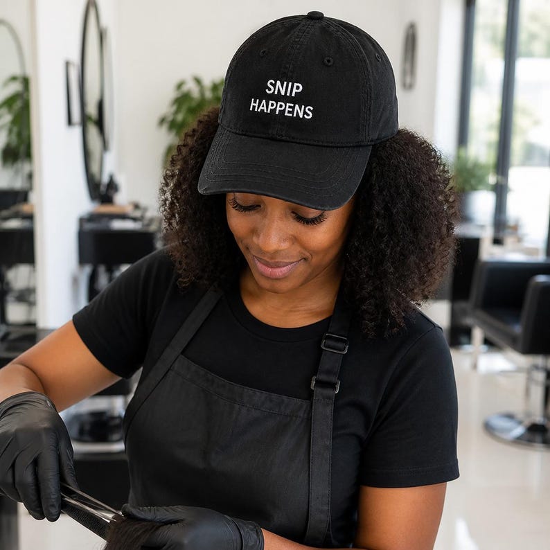 Puede incluir: Una gorra de b&eacute;isbol negra con el texto bordado en blanco SNIP HAPPENS en el panel frontal. La gorra tiene una corona estructurada, una visera curva y una correa ajustable en la parte posterior, ofreciendo un ajuste cl&aacute;sico.