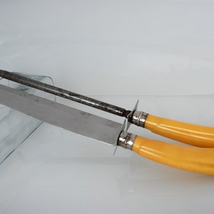 May include: A set of two yellow handled knives with a metal blade and a metal sharpening steel.