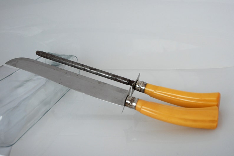 May include: A set of two yellow handled knives with a metal blade and a metal sharpening steel.