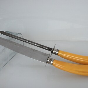 May include: A set of two vintage kitchen knives with yellow plastic handles and a steel sharpening steel.