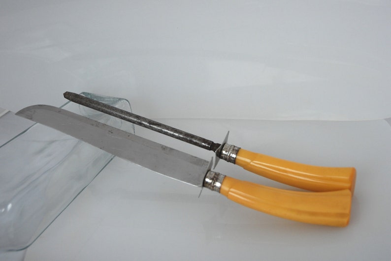 May include: A set of two vintage kitchen knives with yellow plastic handles and a steel sharpening steel.