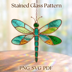 May include: A dragonfly suncatcher featuring a stained glass pattern with teal, green, and amber glass segments held by copper metal cames. The dragonfly is suspended by a metal chain. Text at the top reads Stained Glass Pattern and PNG SVG PDF.