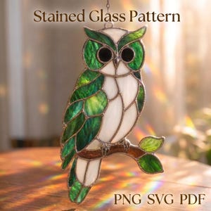 May include: A stained glass suncatcher shaped like an owl perched on a branch, featuring green and white glass segments with dark solder lines. The text Stained Glass Pattern and PNG SVG PDF is visible on the image, which depicts a bird.
