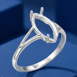 May include: A silver-toned metal ring setting featuring a marquise-shaped head with four prongs designed to hold a gemstone. The band has a split shank design that tapers towards the top, connecting to the central setting with a smooth, polished finish.