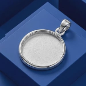 May include: A circular silver pendant featuring a smooth, polished metallic frame and a flat, light grey circular inlay in the centre. The pendant includes a small, integrated silver bail at the top for attachment to a chain or cord.