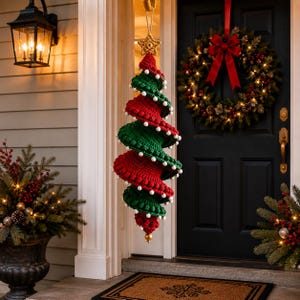 May include: A hanging spiral Christmas tree decoration made of crocheted yarn in alternating red and green sections. The edges of the spiral are trimmed with small white pom-poms. A gold-colored star is attached to the top, and a gold bead is at the base.