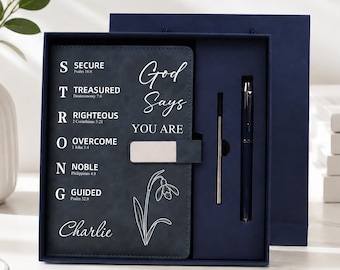 Può includere: Un set di diario blu scuro con chiusura magnetica, una penna abbinata e una ricarica. La copertina mostra il testo God Says YOU ARE, la parola STRONG con riferimenti biblici, un disegno al tratto di un fiore e il nome Charlie in corsivo.