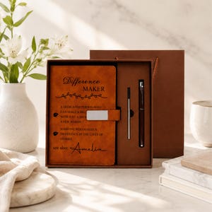 Pu&ograve; includere: Un set di taccuini in similpelle color cuoio con il testo Difference MAKER, a dedicated person who can make a big impact with just a small act or a few words, someone who makes a difference in the lives of others, see also: Amelia, e una penna.