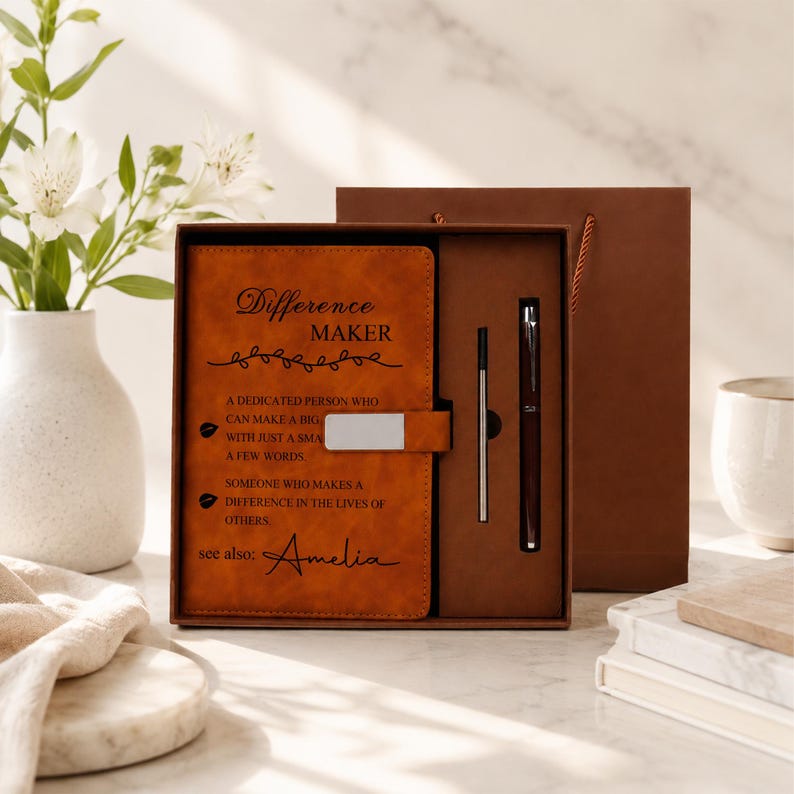 Pu&ograve; includere: Un set di taccuini in similpelle color cuoio con il testo Difference MAKER, a dedicated person who can make a big impact with just a small act or a few words, someone who makes a difference in the lives of others, see also: Amelia, e una penna.