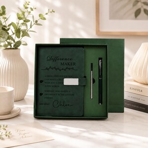 Pu&ograve; includere: Un taccuino verde scuro in una confezione regalo abbinata, dotato di una chiusura in metallo argentato e del testo Difference Maker, a dedicated person who can make a big impact with just a small act or a few words, someone who makes a difference in the lives of others, see also: Chloe, insieme a una penna abbinata.