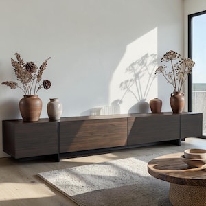 May include: A long, low-profile dark wood media console with a horizontal grain pattern, featuring four cabinet sections. On top sit two large brown ceramic vases with dried floral arrangements and two smaller, smooth ceramic vases.