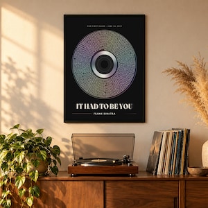 May include: A black framed wall art print featuring a circular vinyl record graphic with iridescent colors. The text reads: OUR FIRST DANCE - JUNE 14, 2019, IT HAD TO BE YOU, and FRANK SINATRA. The design mimics a record label and grooves.
