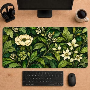 May include: A rectangular desk mat featuring a stained glass style pattern of cream-colored flowers and lush green foliage. The design includes large, multi-petaled blossoms and smaller clusters of white flowers set against a deep green background.