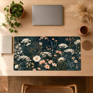 May include: A rectangular desk mat featuring a dark navy blue background densely patterned with a variety of white and soft peach-colored wildflowers, including clusters of small blossoms and larger daisy-like flowers with green foliage.