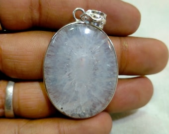 May include: A white oval pendant with a silver bail. The pendant is made of a clear crystal with a white, cloudy, and sparkly appearance.