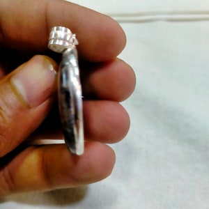 May include: Silver pendant with a textured, rounded design. The pendant has a loop at the top for attaching to a chain.
