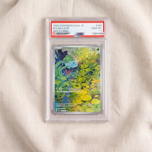 Könnte beinhalten: Eine bewertete 2023 Pokemon SV2a JP Bulbasaur Sammelkarte in einer durchsichtigen Kunststoffhülle. Die Karte zeigt eine farbenfrohe Illustration eines Bulbasaur in einem dichten grünen Wald mit dem aufgedruckten Text Bulbasaur, 70 HP und Leech Seed 20.