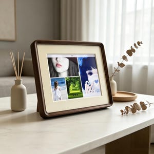 May include: A digital photo frame with a dark wood frame and a cream-colored mat displays a collage of four images: a close-up of a person, a person in a white dress on a beach, a green forest path, and an illustration of a person with a blue bow.
