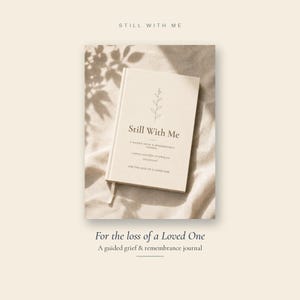 May include: A cream-coloured hardback journal titled Still With Me, A Guided Grief & Remembrance Journal, For The Loss Of A Loved One. The cover features a simple line drawing of a sprig and dark text. A ribbon bookmark extends from the bottom edge.